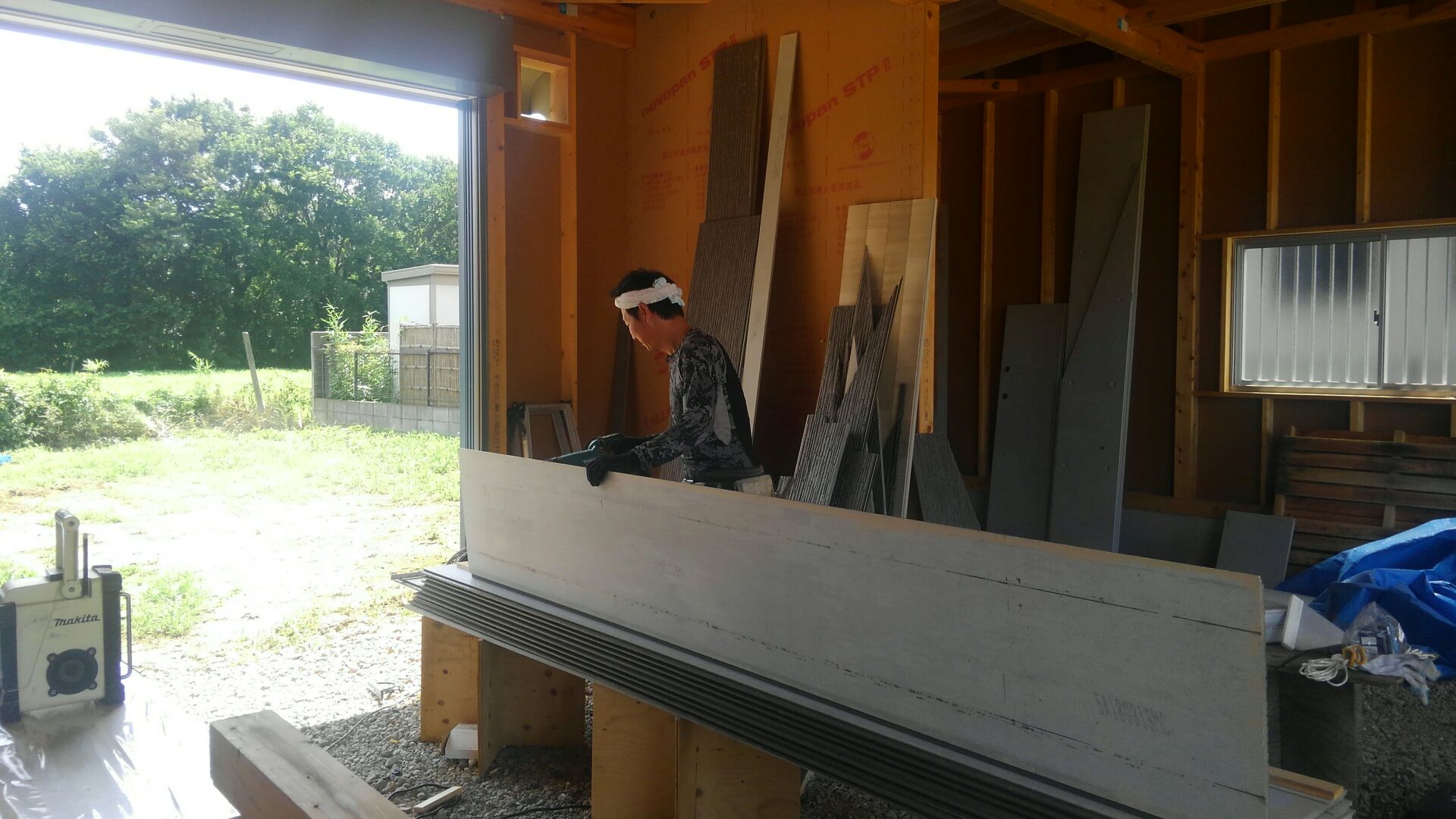 先日、自前のテントで作業をしていたサイディング屋さん。ヤッパリ西日がつらかったのか、今度はガレージの中で加工です。初めからそうすればよかったのに（＾＾；涼しげな顔で作業中！